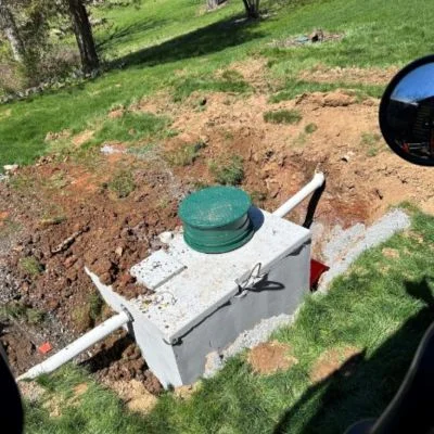 Newly installed septic tank with green cover in excavated yard area