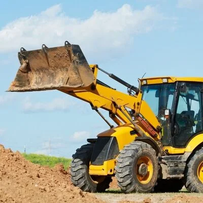 Yellow wheel loader with raised bucket full of excavated soil on construction site