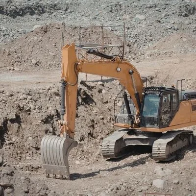 Tracked excavator with bucket performing soil excavation and site grading