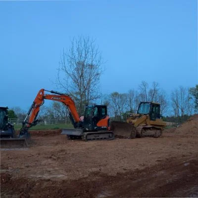Red mini excavator and yellow dozer grading bare earth site during excavation work