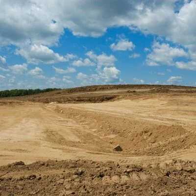 Aerial view of excavated site with graded earth, access roads, and cleared land preparation